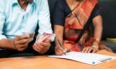 close up shot of Senior couple hands busy checking budget or bill spending at home- concpet of...