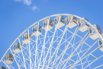 Ferris wheel on a blue sky. Amusement park. Empty ferris wheel on sunny day in Kyiv, Ukraine. Summer recreation. Leisure activity. Big circle Vintage carousel on blue sky. Outdoors attraction.