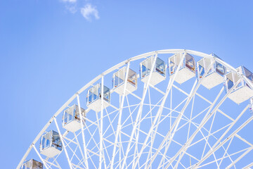 Ferris wheel on a blue sky. Amusement park. Empty ferris wheel on sunny day in Kyiv, Ukraine. Summer recreation. Leisure activity. Big circle Vintage carousel on blue sky. Outdoors attraction. - obrazy, fototapety, plakaty