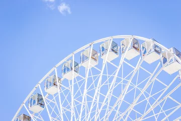 Fotobehang Ferris wheel on a blue sky. Amusement park. Empty ferris wheel on sunny day in Kyiv, Ukraine. Summer recreation. Leisure activity. Big circle Vintage carousel on blue sky. Outdoors attraction. © Nataliia