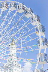 Ferris wheel on blue sky and city tower. Amusement park. Empty ferris wheel on sunny day in Kyiv,...