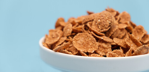 Durum wheat flakes - quick breakfast cereal on a plate on a light blue background.