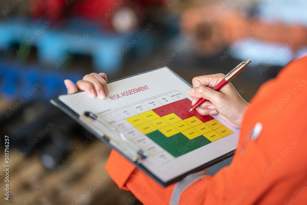 Wall mural action of a person is using ballpoint pen to marking on the risk assessment matrix table at 