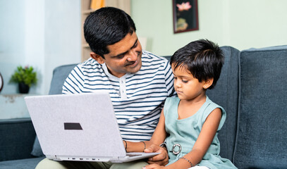 happy Father helping or teaching the daughter to use laptop at home - concept of home schooling, parental teaching and development