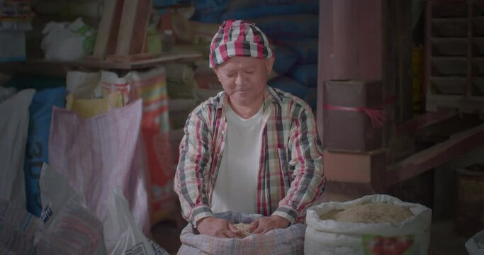 A happy smiling Asian farmer man with turban scoop up mixed rice that has just been milled Including jasmine rice, brown rice and riceberry rice.