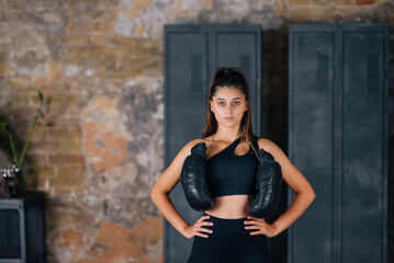 Fototapeta premium Sporty woman in sportswear posing on camera with boxing gloves.