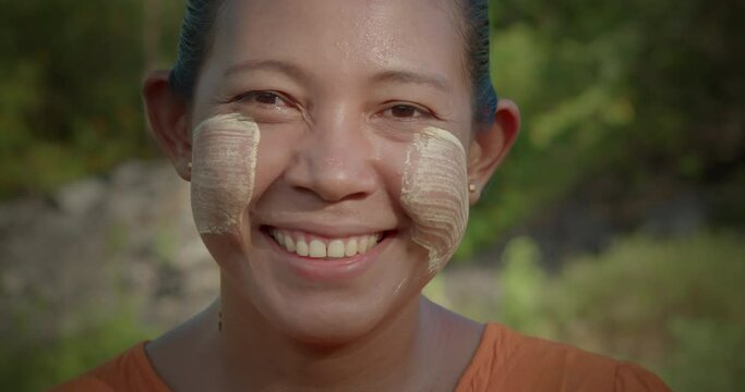 A happy smiling Burmese female farmer woman who powder to their cheeks, known as "Thanaka".