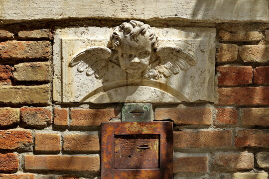 Tête d'ange sculptée au dessus d'une boîte aux lettres. Façade ancienne. 