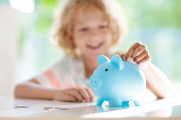 Child putting coin in piggy bank. Kids and money.