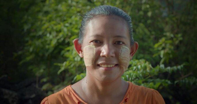 A happy smiling Burmese female farmer woman who powder to their cheeks, known as "Thanaka".