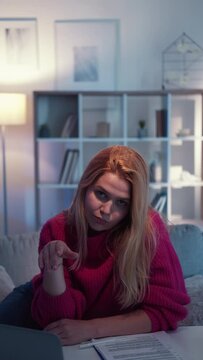 Boring woman. Silly face. Uninterested news. Skeptic careless lady waving hand rolling eyes showing displeased feelings of task sitting desk light room interior vertical.