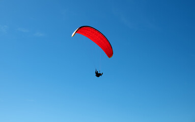 The sportsman flying on a paraglider. Silhouette on blue sky.
Paragliding take off. Travel destination. Summer and holiday concept. 