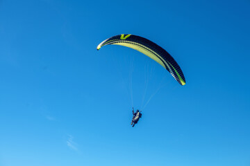 The sportsman flying on a paraglider. Silhouette on blue sky.
Paragliding take off. Travel destination. Summer and holiday concept. 