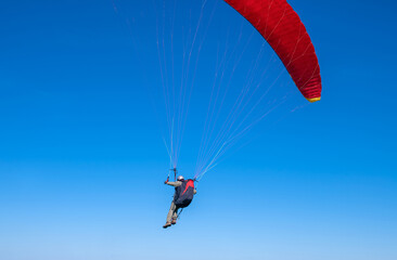 The sportsman flying on a paraglider. Silhouette on blue sky.
Paragliding take off. Travel destination. Summer and holiday concept. 