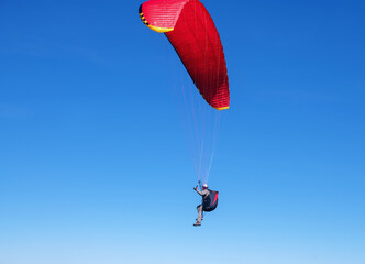 The sportsman flying on a paraglider. Silhouette on blue sky.
Paragliding take off. Travel destination. Summer and holiday concept. 