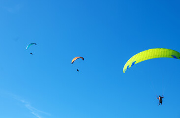The sportsman flying on a paraglider. Silhouette on blue sky.
Paragliding take off. Travel destination. Summer and holiday concept. 
