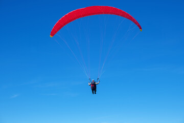 The sportsman flying on a paraglider. Silhouette on blue sky.
Paragliding take off. Travel destination. Summer and holiday concept. 