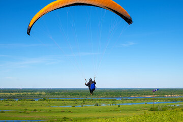 The sportsman flying on a paraglider. Silhouette on blue sky.
Paragliding take off. Travel destination. Summer and holiday concept. 