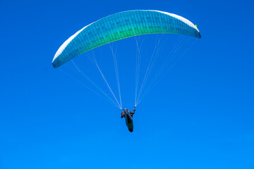 The sportsman flying on a paraglider. Silhouette on blue sky.
Paragliding take off. Travel destination. Summer and holiday concept. 