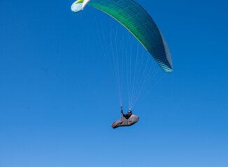The sportsman flying on a paraglider. Silhouette on blue sky.
Paragliding take off. Travel destination. Summer and holiday concept. 