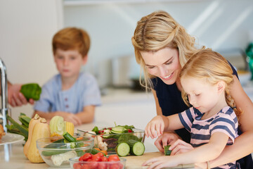 Shes a great little chef. Cropped shot of a mother cooking together with her two kids at home.