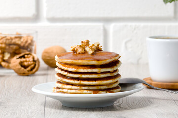 a stack of delicious pancakes poured with syrup, with walnuts and a cup of aromatic coffee. delicious healthy breakfast
