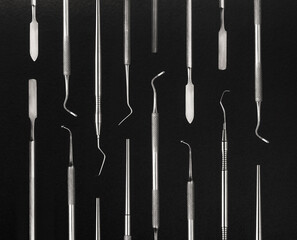 Set of dental metal instruments for treating and checking teeth. Top view on black background