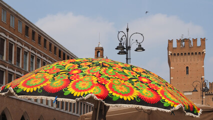 Flea market. The umbrella of a stall and the Torre della Vittoria in the background, as if to say that summer has arrived in the city.