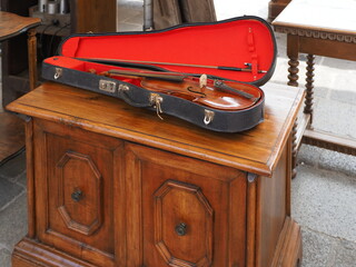 Flea market. A violin in its case rests on a wooden cabinet.