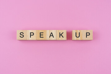 Speak up spelling on wood block pink background