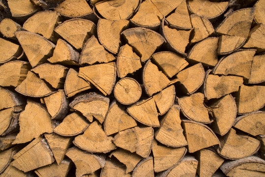 Background with stacked pieces of wood. Dominant yellow dry logs, natural fuel for heating, firewood. Pieces of pine and fir to burn.
