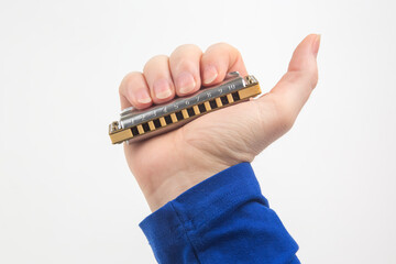 The right hand holds a harmonica on a white background. Classical musical wind instrument.