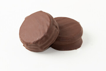 Two black chocolate alfajor isolated on white background.