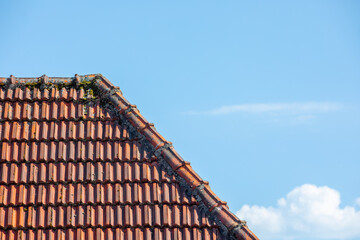 Fototapeta premium View of old tile roof against blue sky