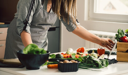 Unrecognizable Woman Reading Recipe On A Digital Tablet While Cooking Healthy Lunch At The Kitchen Desk
