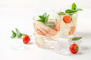 Summer refreshing iced drinks with cucumber,  strawberry and mint on white background. Infused water