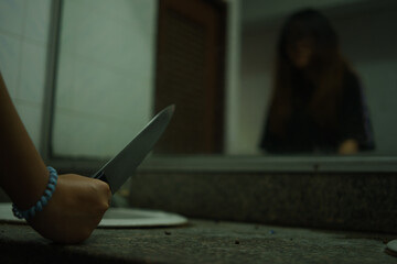 Behind the murder woman holding a knife and looking in the mirror in the bathroom.Scary horror or...