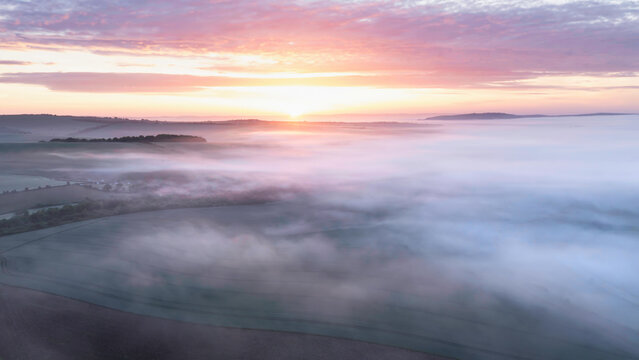 Majestic drone landscape image of sea of fog rolling across South Downs English countryside during Spring sunrise