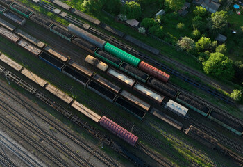 Railway yard with freight rail wagons. Cargo trains with goods on railroad. Freight train with petroleum tank cars and shipping containers. Train yard, aerial view. Rail Freight Shipping Logistics.