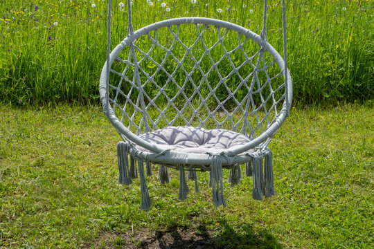 Decorative resting place in the form of a wicker swing suspended from a tree in an summer park