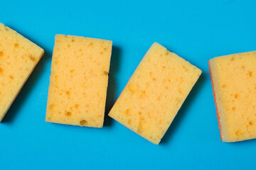 Yellow porous sponges for cleaning on a blue background with copy space