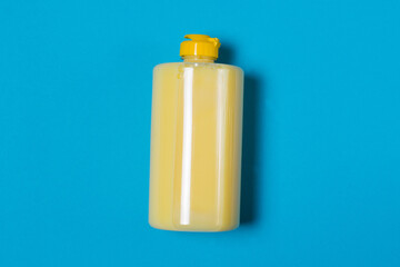 Yellow dishwashing detergent with banana scent on a blue background with copy space