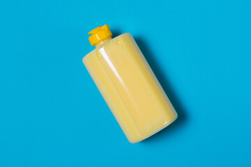 Yellow dishwashing detergent with banana scent on a blue background with copy space