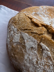 Close up of a loaf of sourdough bread on a wooden board with white napkin