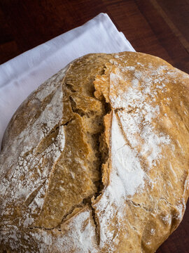 Angled, close up of a loaf of sourdough bread on a wooden board