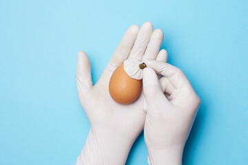 hands in medical gloves holding egg with ice bag