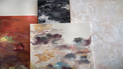 Artworks. Closeup view of four abstract modern paintings laying against the wall. Beautiful color palette and texture.       