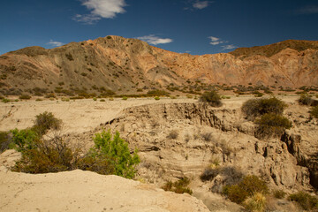 Arid environment. View of the sandstone cliffs, canyon, rocky mountains and desert sand, under a deep blue sky.	