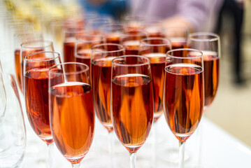 Champagne Rose glasses on the bar. Lots of glasses with drinks. Bright colored lights behind the glasses.