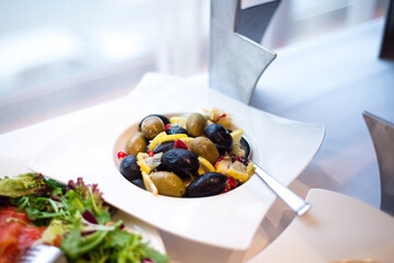 Plate with olives. Served on a plate with lemon. A buffet line with appetizers.